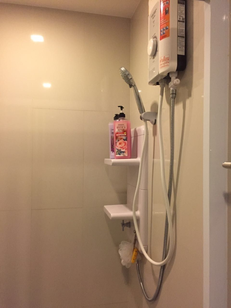 A shower with a handheld showerhead and a wall-mounted control panel.