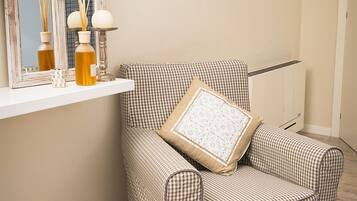 A checkered armchair with a cushion, a mirror with a wooden frame, and a shelf with decorative items.