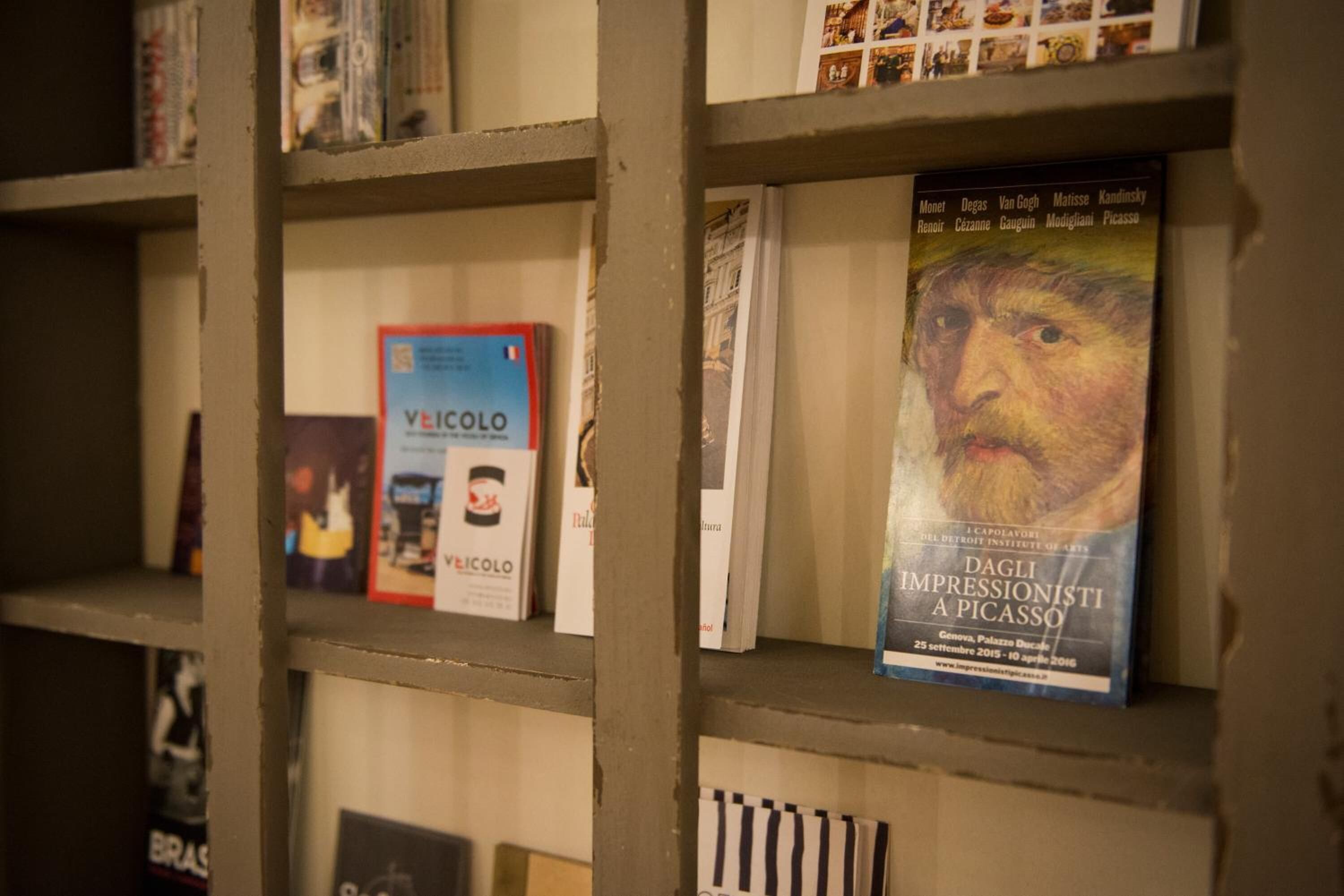 A bookshelf with various books and magazines, including a book titled "DAGLI IMPRESSIONISTI A PICASSO".
