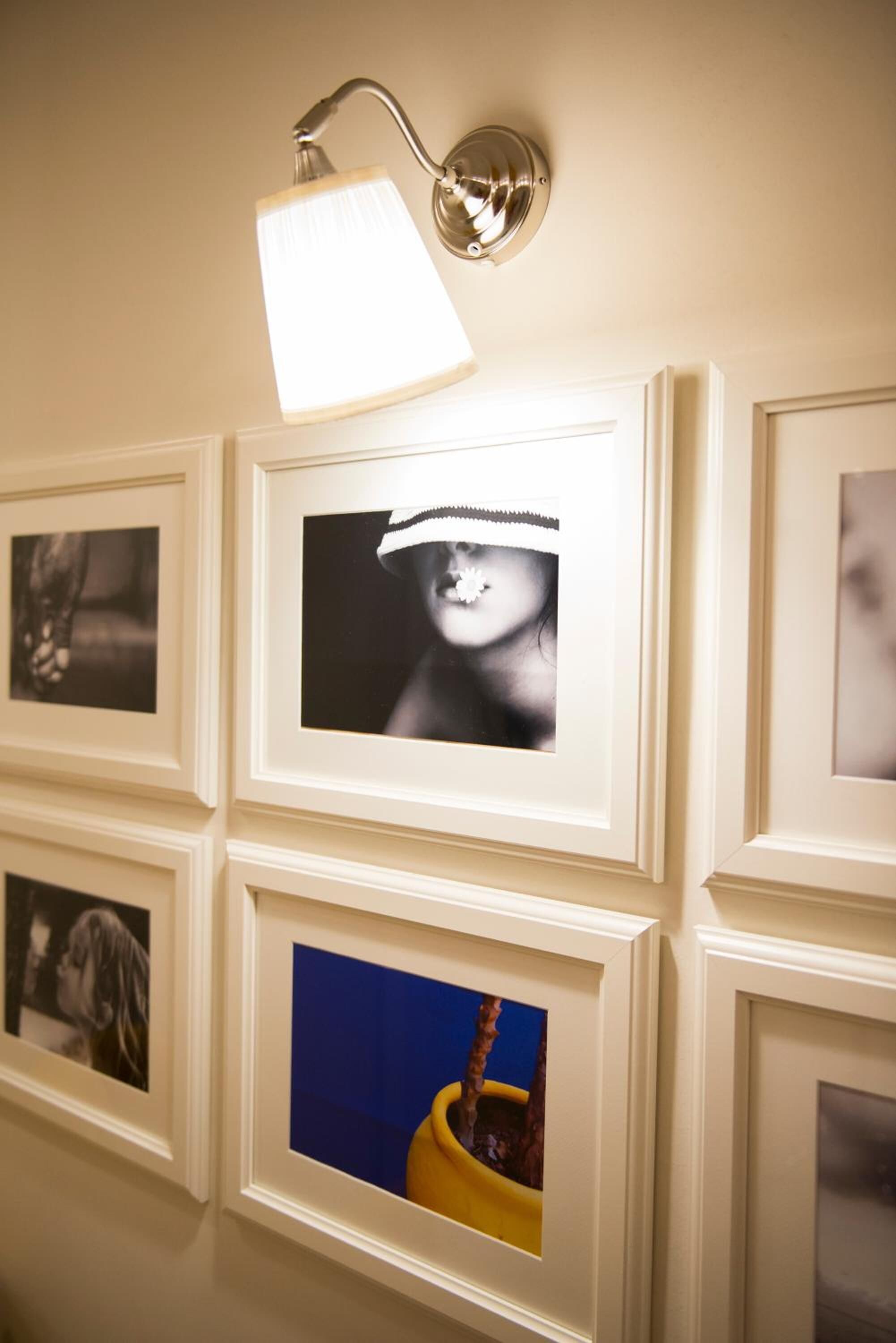 A wall with framed photographs and a wall-mounted light fixture.