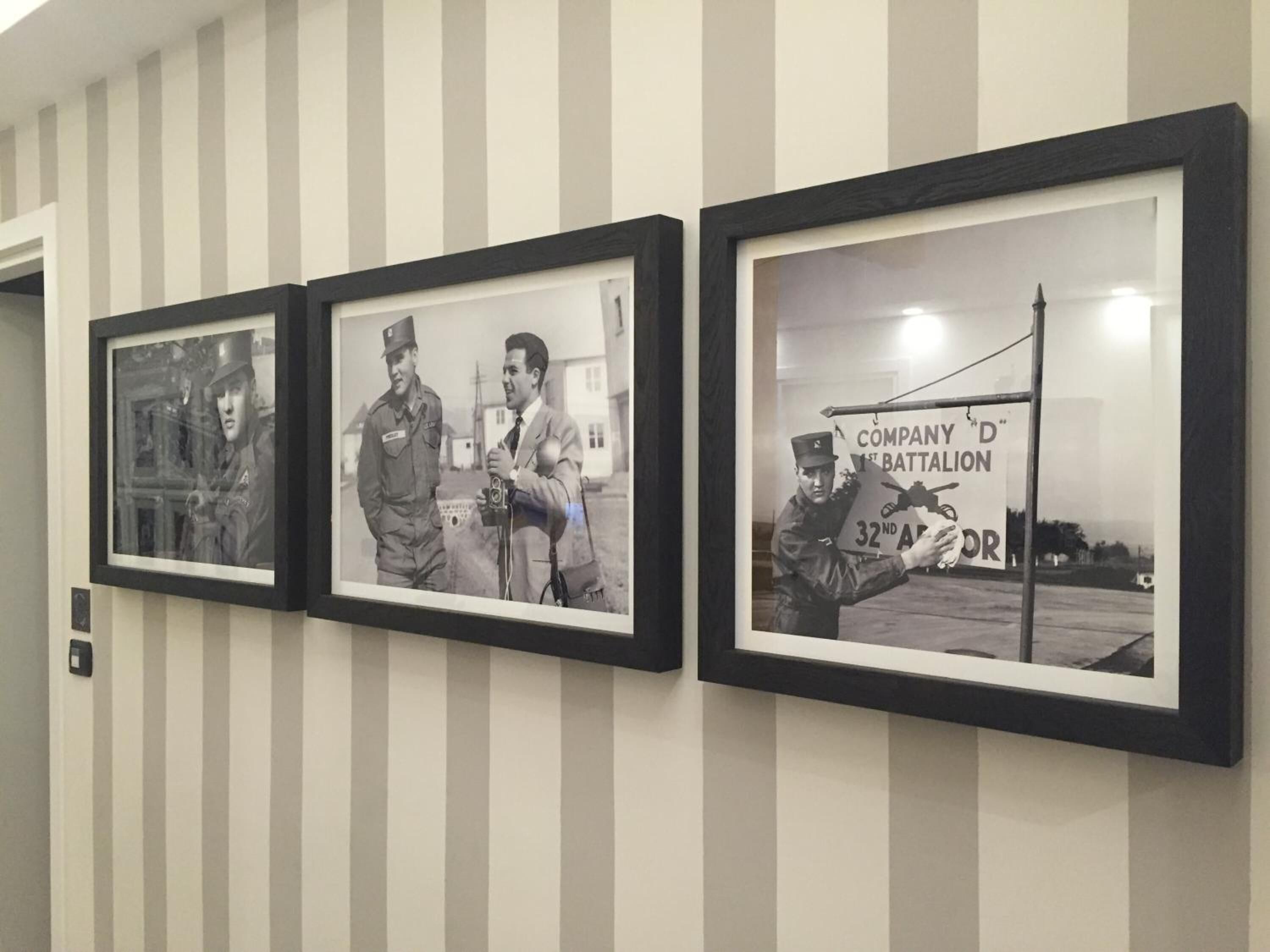 Three framed photographs on a wall with vertical stripes.
