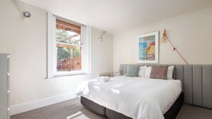 Un dormitorio con una cama, una ventana, una lámpara en la pared y un cartel.