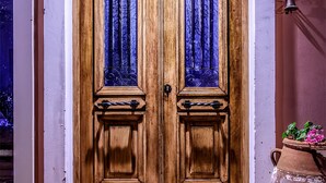 A wooden double door with decorative ironwork and glass panels, leading to a tiled entrance area. - Villa Elise, Beautiful house, A/C, Private Pool, Table Tennis . (Kokkini Hani, Heraklion, Crete)