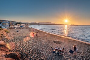 Une plage avec des parasols, des chaises longues et un poste de surveillance pour les sauveteurs.