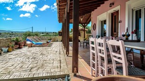 A covered outdoor seating area with a table and chairs, potted plants, and a view of the landscape. - Villa Elise, Beautiful house, A/C, Private Pool, Table Tennis . (Kokkini Hani, Heraklion, Crete)