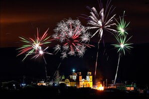 Une scène nocturne avec des feux d’artifice illuminant un bâtiment, qui pourrait être une église ou un site historique.