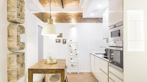Una cocina moderna con armarios de madera, horno empotrado y un comedor con mesa y sillas de madera.
