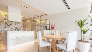 A modern dining area with a round wooden table, white upholstered chairs, and a white console table with a glass top. - Beautiful apartment in the centre of Madrid (Madrid)