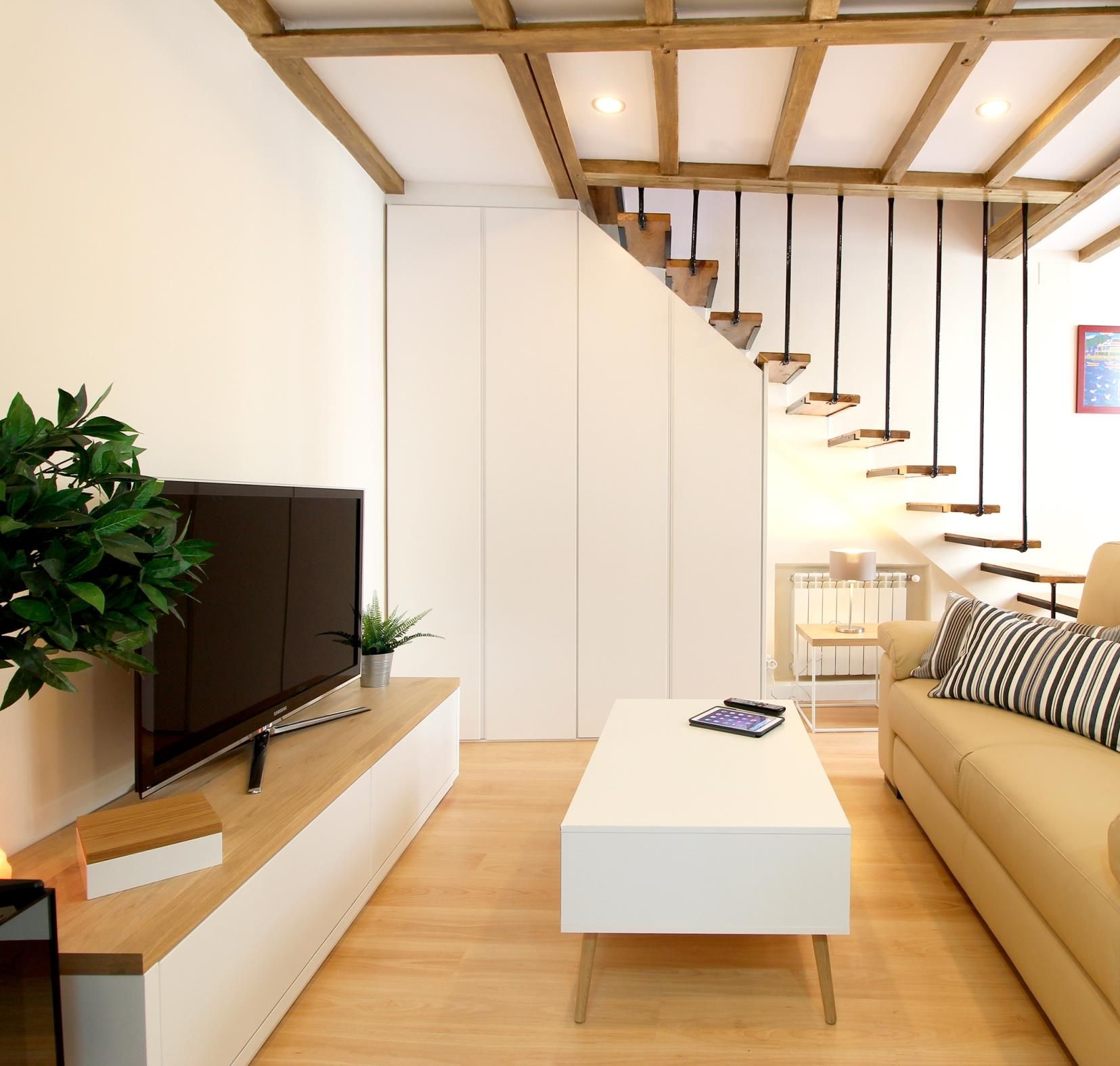 Ein modernes Wohnzimmer mit einer Couch, einem Couchtisch, einem Fernseher und einer Treppe.