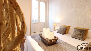 A hotel room with a bed, a wicker basket with towels, a lamp, and patterned wallpaper. - Huertas studio - Apartment in the center of Madrid (Madrid)