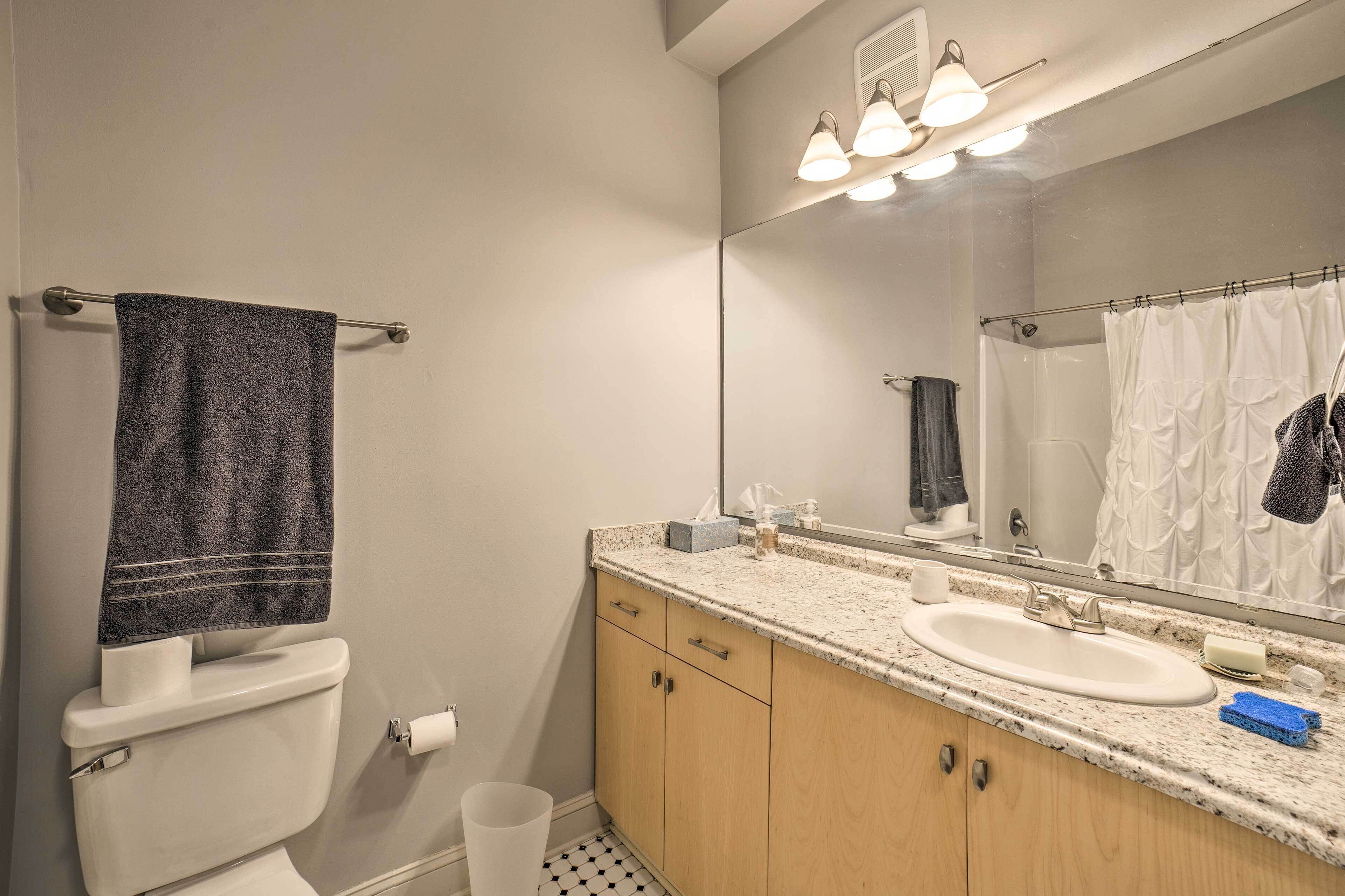 Une salle de bain équipée de toilettes, d’un lavabo, d’un miroir et d’un porte-serviettes.