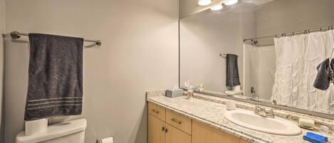 Une salle de bain équipée de toilettes, d’un lavabo, d’un miroir et d’un porte-serviettes.