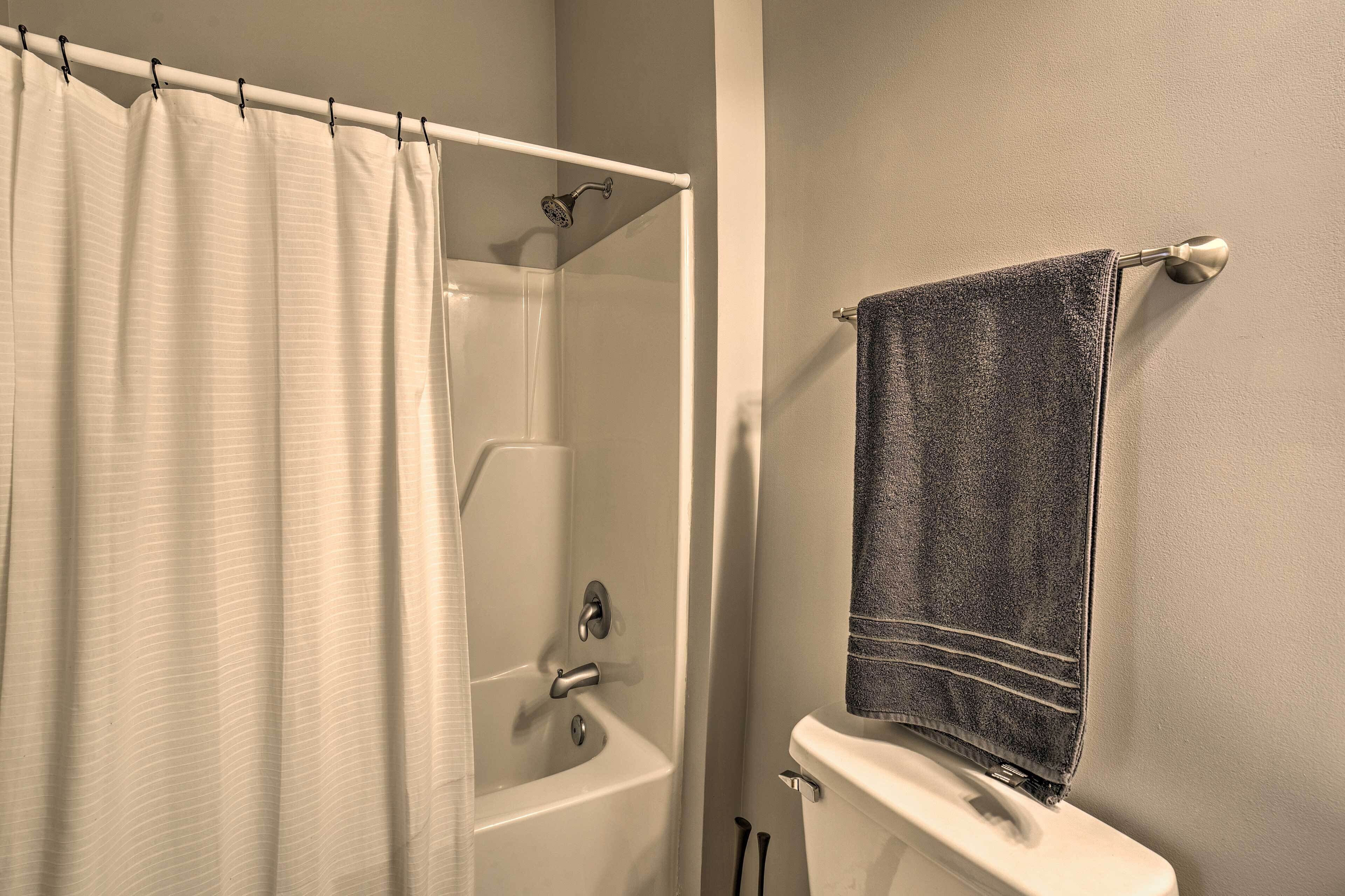 A bathroom with a shower curtain, a bathtub, a toilet, and a towel hanging on a rack.