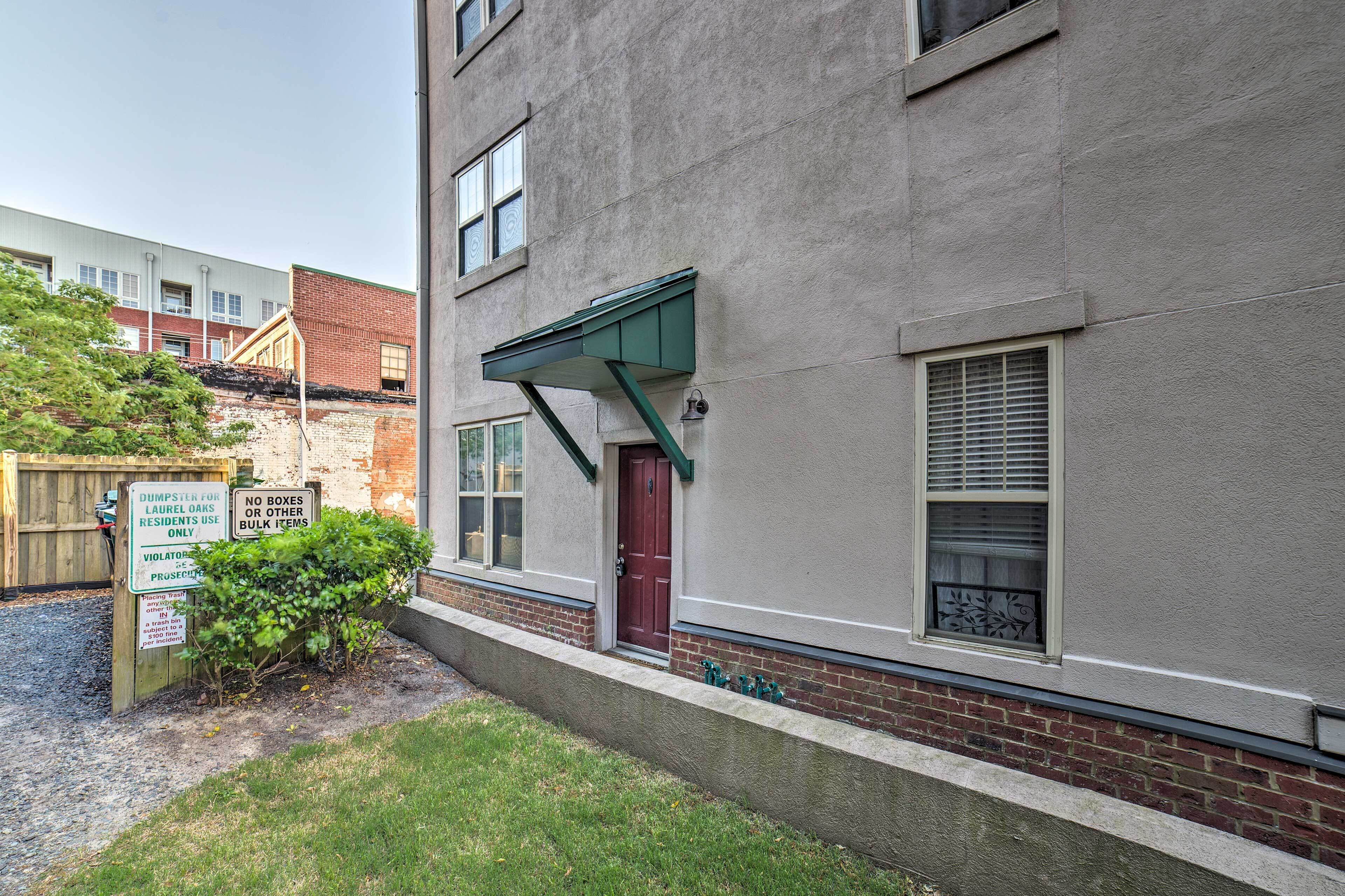 A building with a red door, a green awning, and a sign indicating a dumpster for residents.
