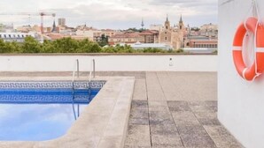 Piscina no terraço com vista para a cidade, um salva-vidas e uma borda estampada.