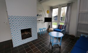 Relax by the fireplace in this inviting living area, featuring a comfortable sofa, flat-screen TV, and a small table for gathering.