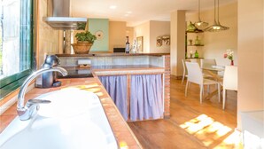 Una cocina moderna con un lavamanos grande, una estufa y un comedor con mesa y sillas.