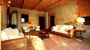 A cozy living room with wicker furniture, stone walls, and a tiled floor. - Podere Lucignano Secondo Agriturismo (Gaiole in Chianti)