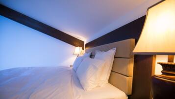 A neatly made bed with white linens, a wooden headboard, and a bedside lamp.