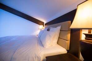 A neatly made bed with white linens, a wooden headboard, and a bedside lamp. - Branmontecrai (Bran)