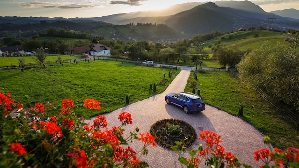 A scenic view of a rural area with a paved pathway leading to a blue car parked on a grassy area. - Branmontecrai (Bran)