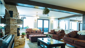 A spacious living room with a piano, sofas, and a fireplace. - Branmontecrai (Bran)