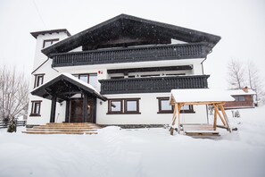 A multi-story building with a snow-covered roof and steps leading to the entrance. - Branmontecrai (Bran)