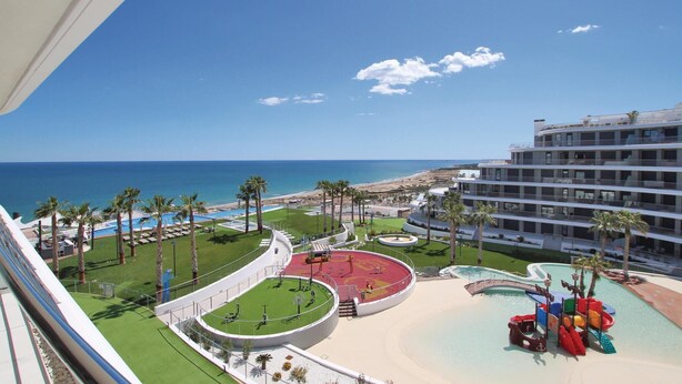 A resort with a pool area, a beach, and a view of the ocean. - Luxurious apartment in Elche with sauna (Elche)