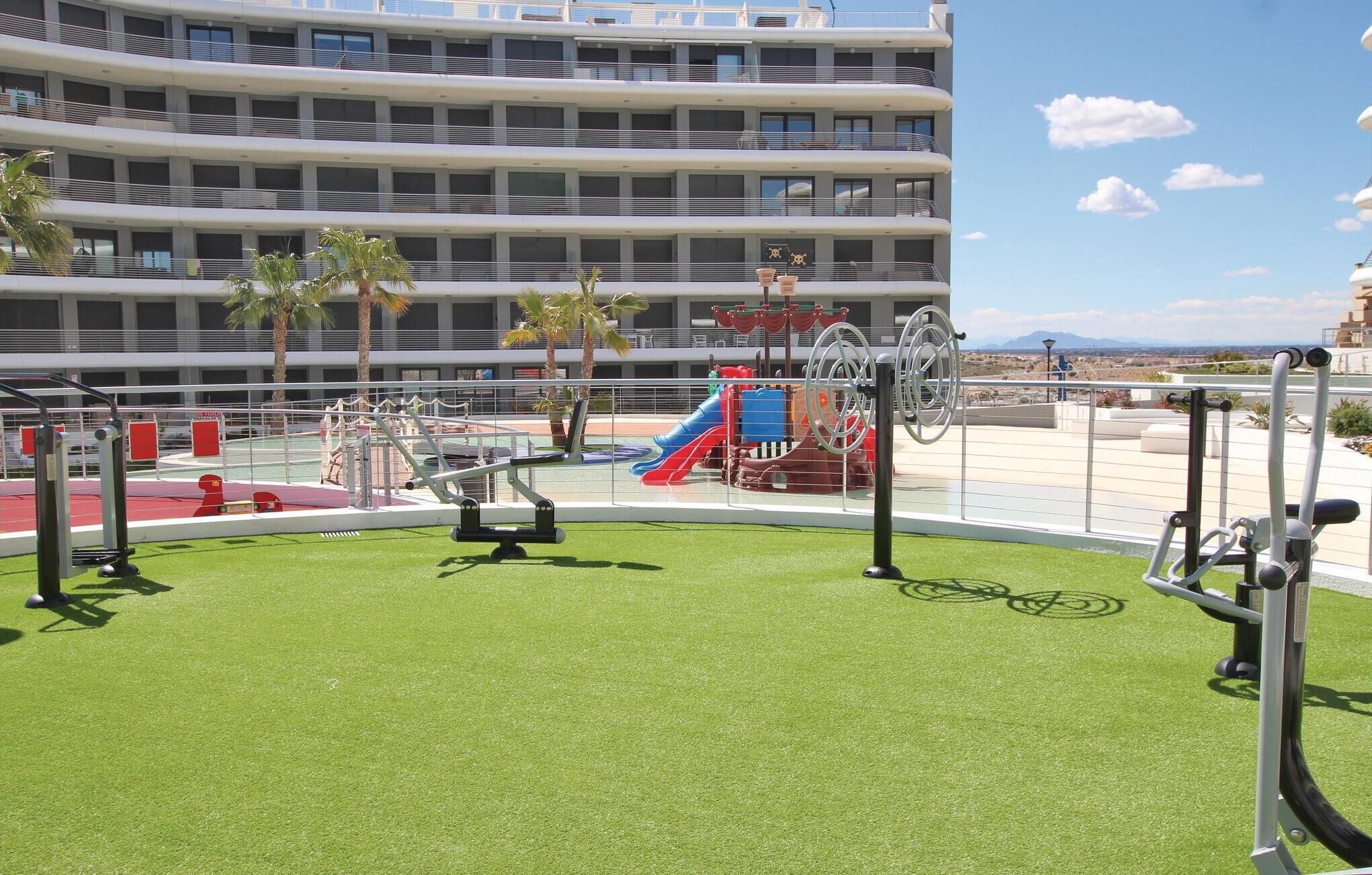 Gimnasio en la azotea con equipamiento de ejercicio y zona de juegos infantiles.