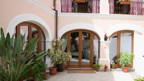 Un patio con arcos, plantas en macetas y suelo de baldosas.