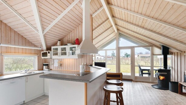 Una cucina moderna con isola centrale, mobili bianchi e un'ampia finestra che offre vista sull'esterno.