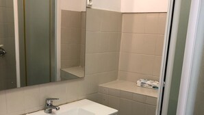 Un baño con lavamanos blanco, espejo y armario de almacenamiento.