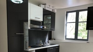 Una cocina moderna con armarios negros, horno empotrado y ventana que aporta luz natural.