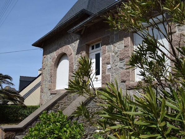 Traditional stone building with an arched entrance, surrounded by lush greenery and tropical plants.