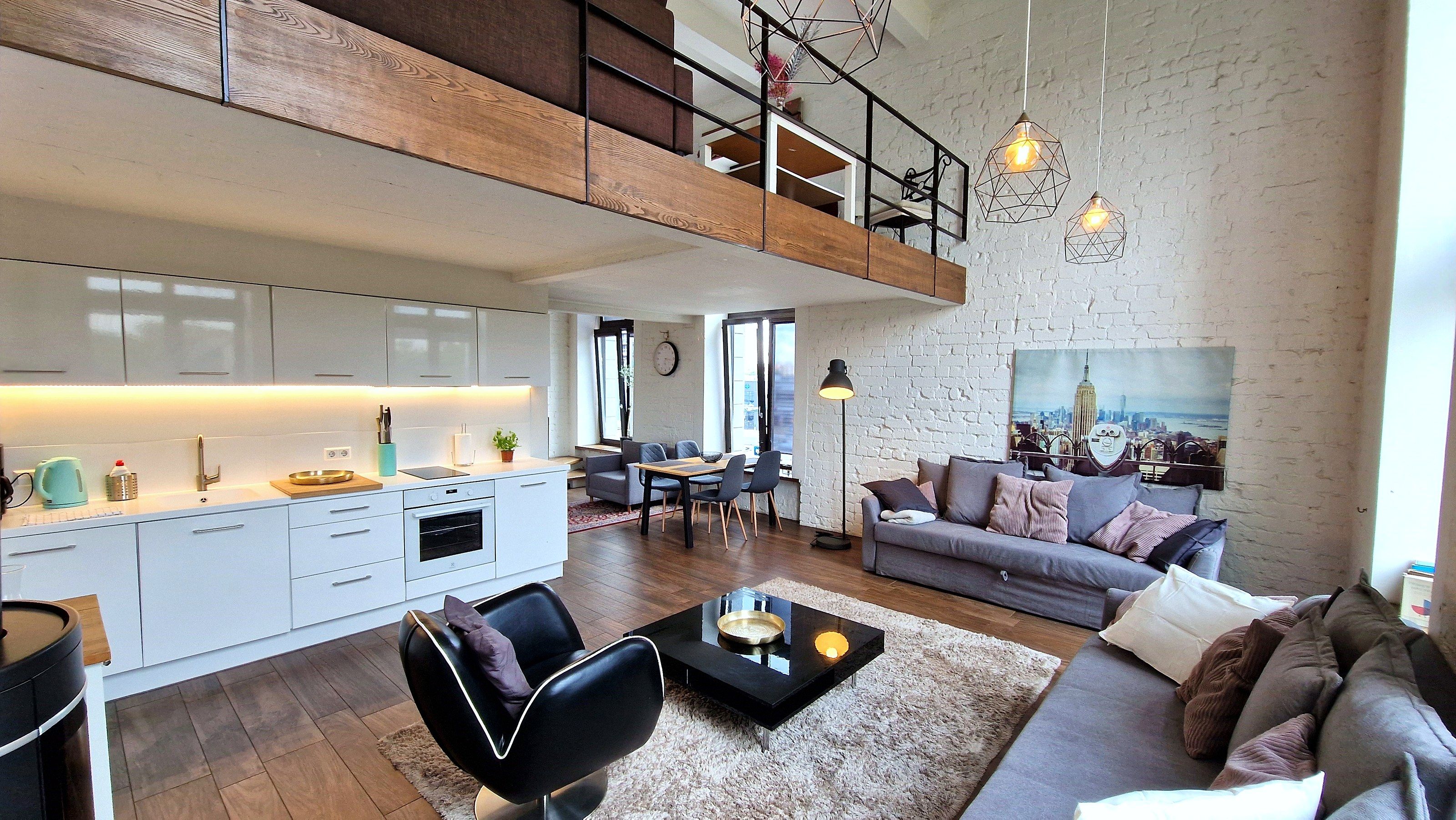 A modern loft-style living space with a kitchen, dining area, and seating area.