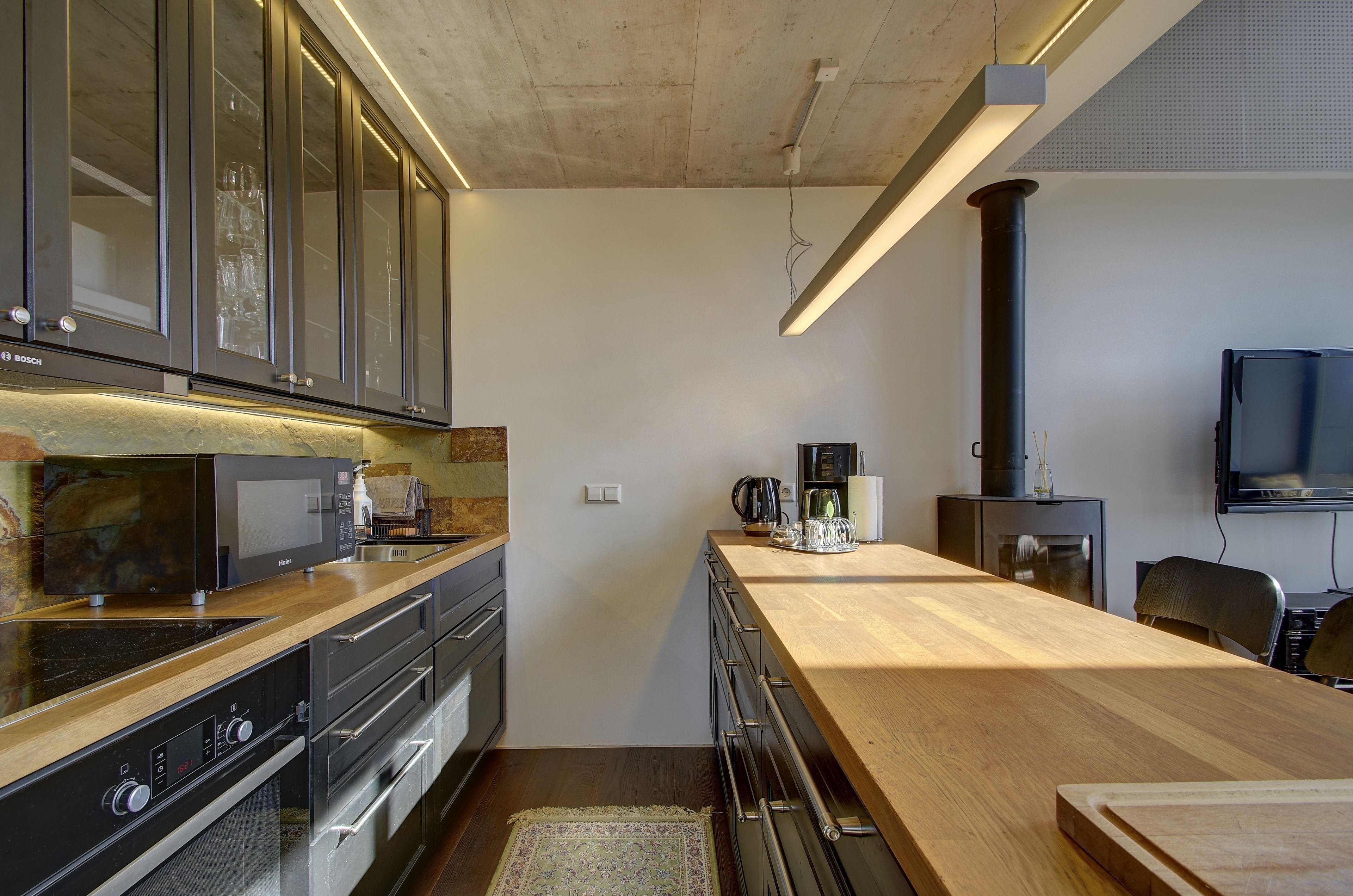 Una cocina moderna con electrodomésticos integrados, encimera de madera y un ventanal grande.