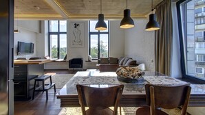 Ein modernes Wohnzimmer mit Essbereich, großen Fenstern und Blick auf die Stadt.