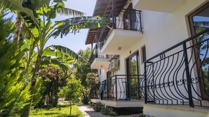 A two-story building with balconies, a garden with banana trees, and a pathway leading to the entrance. - Karia Apart (Datça)