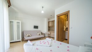A bedroom with a bed, a sofa, a TV, and a wardrobe. - Karia Apart (Datça)