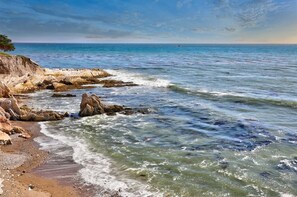 Een kuststrand met rotsformaties en helderblauw water.