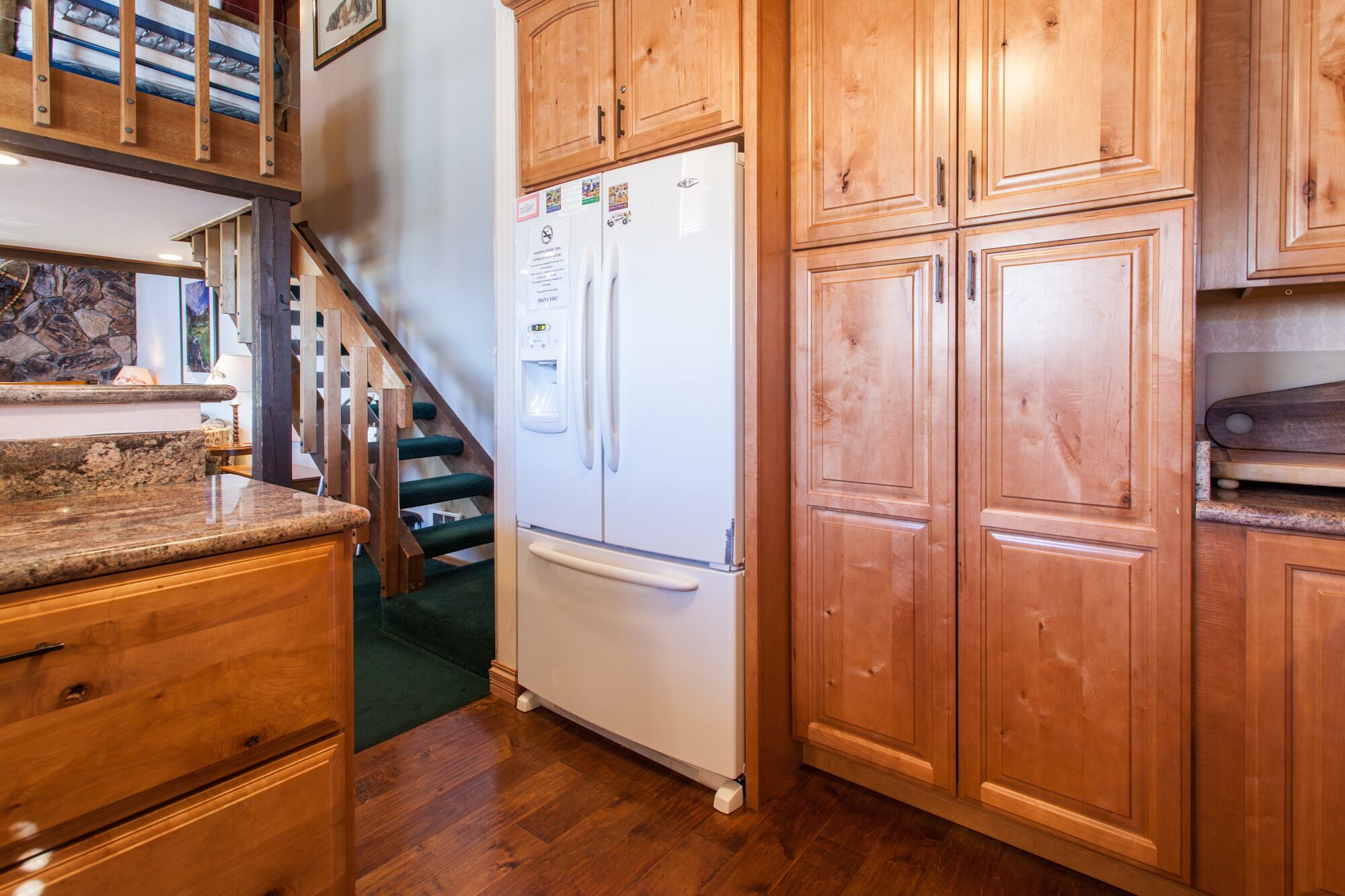 A kitchen with wooden cabinets, a white refrigerator, and a granite countertop.