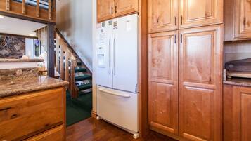 A kitchen with wooden cabinets, a white refrigerator, and a granite countertop.