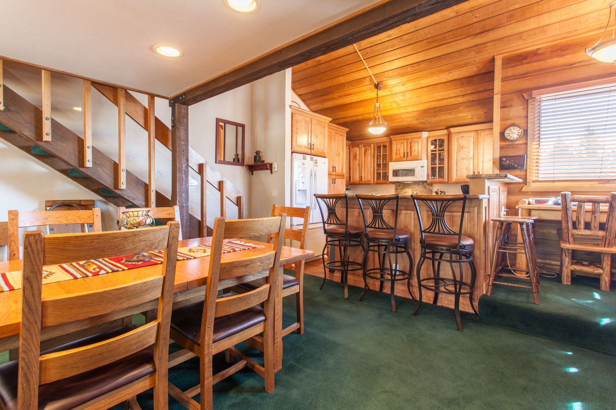 A wooden interior with a dining area, kitchen, and staircase.