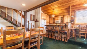 A wooden interior with a dining area, kitchen, and staircase.