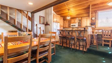 A wooden interior with a dining area, kitchen, and staircase.