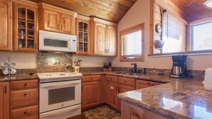 A kitchen with wooden cabinets, a microwave, an oven, and a coffee maker.