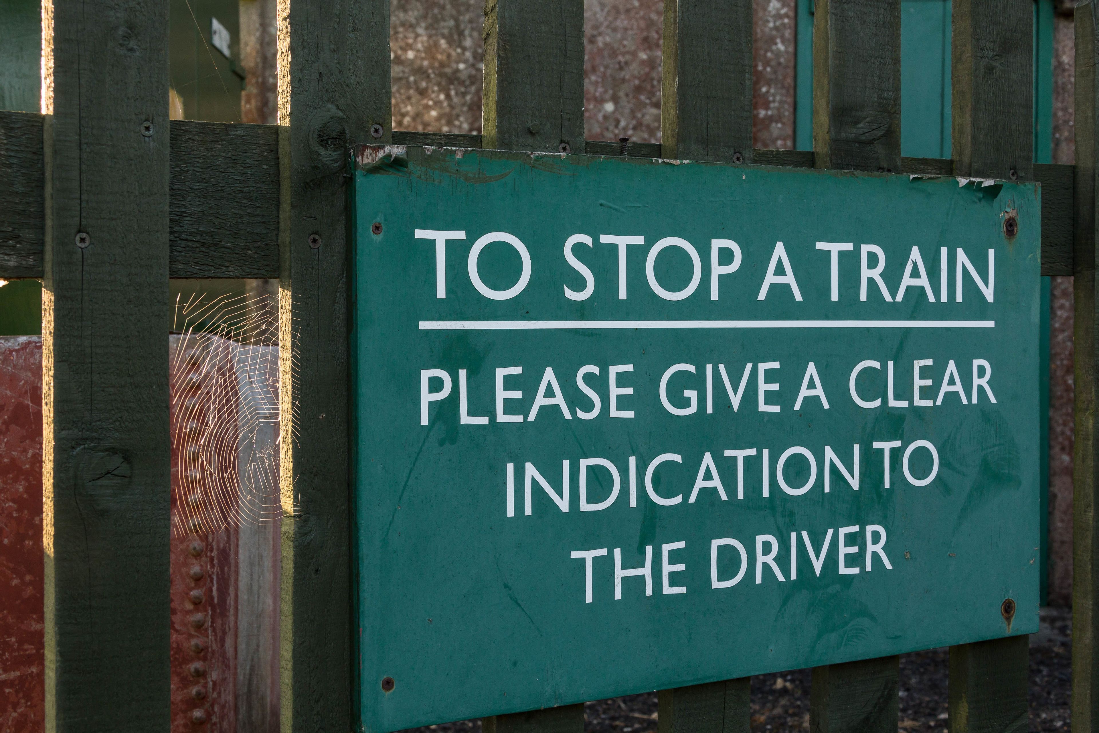A green sign with white text on a wooden fence.