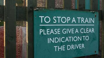 A green sign with white text on a wooden fence.