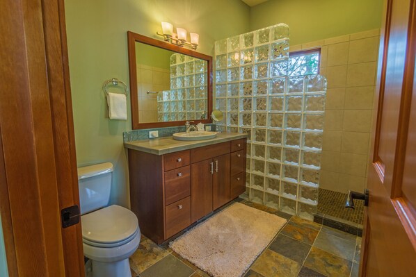 Une salle de bain avec un meuble-lavabo en bois, une cabine de douche en verre et un carrelage au sol.