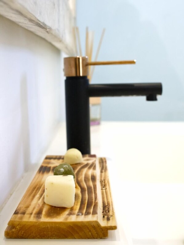 Una tabla de madera con dos alimentos: un cubo blanco y una esfera verde, sobre una superficie blanca.